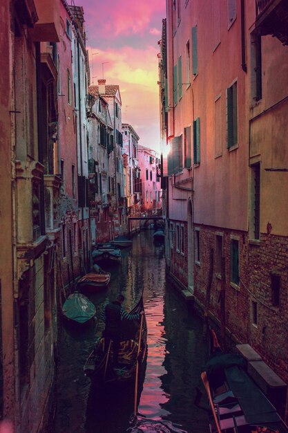 Canal amidst buildings in city during sunset