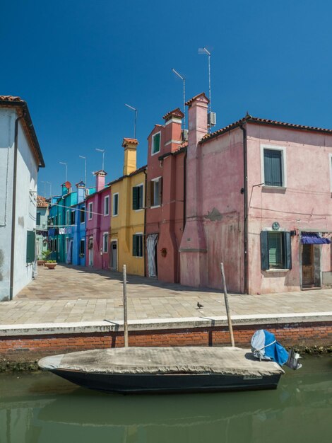 Canal by buildings against blue sky