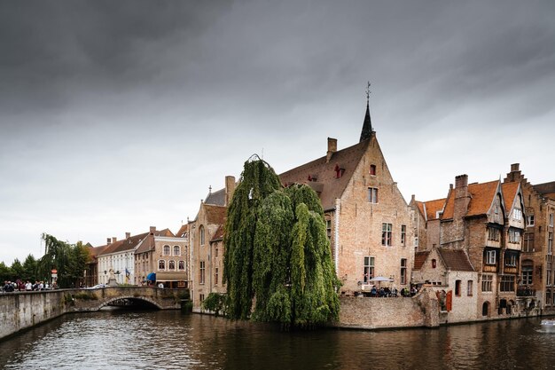 Canal by buildings against cloudy sky