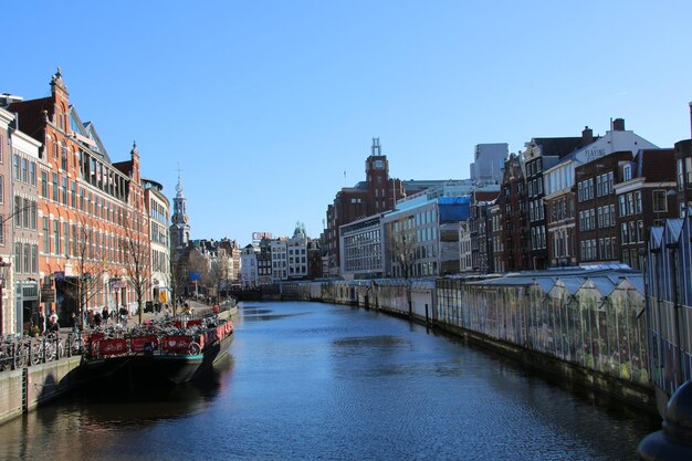 Canal in city against clear sky