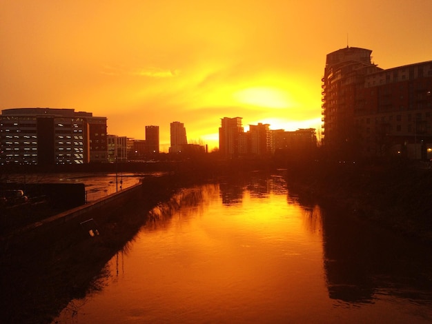 canal in city against sky during sunset