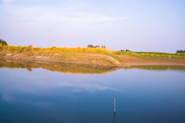 Canal with green grass and vegetation reflected in the water nearby Padma river in Bangladesh