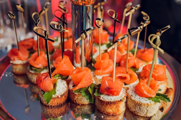 Canape appetizers on the table buffet menu European cuisine shrimp mini burger on a wooden background