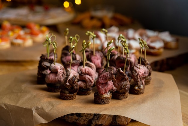 Foto canape con carne di manzo su spiedini su un tavolo di legno canape nel ristorante su tavolo a buffet