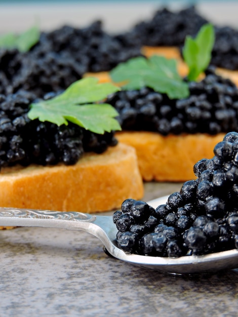 Canapé with black caviar and greens.