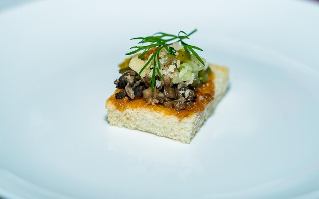 Canape with mushrooms and cheese on a white plate in a restaurant