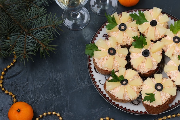 Canapes met roomkaas, krabsticks, zwarte olijven en ananas op donker