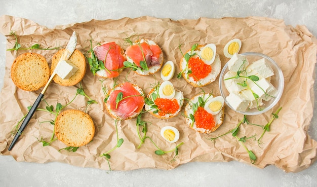 Canapes with red caviar and red fish on paper Food background