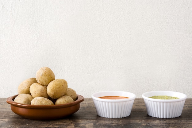 Canarian potatoes (papas arrugadas) with mojo sauce on wooden table