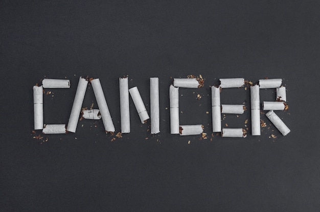 Фото Рак - это надпись, сделанная из сломанных сигарет, чтобы визуализировать вред курения. против курения - против рака.