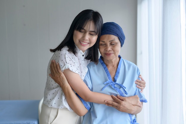 Cancer patient woman wearing head scarf and her supportive daughter in hospital