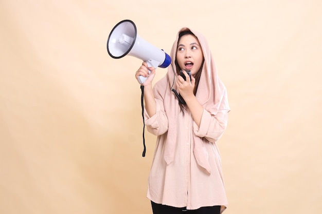 Candid Asian woman with her right hand holding audio and carrying a megaphone loudspeaker shouted