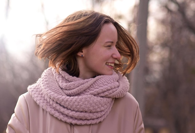 Candid attractive young smiling woman walking in autumn park happy mood fashion style trend pink jacket waving brown hair