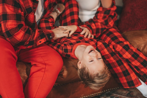 Candid authentic cute happy family in red plaid pajamas spends time together at lodge Xmas decorated