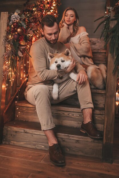 Candid authentic happy married couple spends time together with japanese dog at Xmas lodge