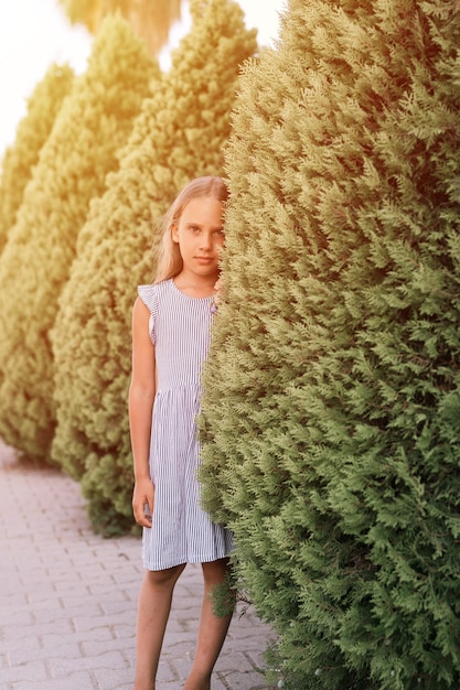 Candida caucasica felice bambina di otto anni con lunghi capelli biondi e occhi verdi su sfondo di piante verdi durante una vacanza estiva viaggio gen z concetto di salute mentale bagliore