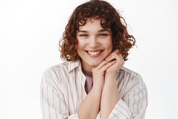 candid happy girl, showing true authentic emotions, laughing and smiling, holding hands near face cute, standing on white