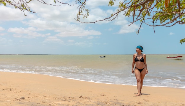 Foto un momento candido una donna in bikini che cammina su una spiaggia deserta lungo la costa settentrionale di guajira
