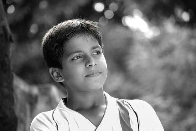若いインドの少年の肖像画の率直な写真は、白黒で距離を見ている顔をクローズアップ