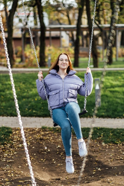 Candid portrait of beautiful young woman on swing on spring day outdoors happy student teenager girl
