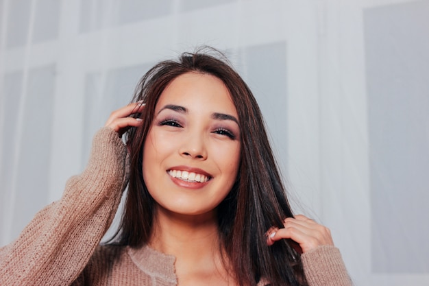 Candid portrait of sensual smiling asian girl young woman with dark long hair in cozy beige sweater