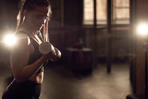 Candid strong young woman is training with a dumbbells in the gym Real wokout