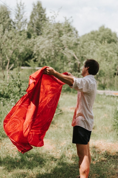 Candid young mature choring man chore homework and hanging the laundry to dry on a clothesline on the street in courtyard of village household cottage house summer freshness and laundry day