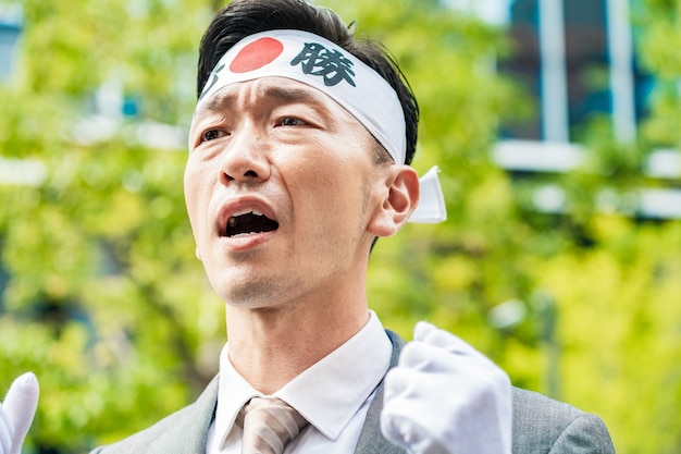 A candidate for elections with headbands to raise their voices.
The characters written on the headband are in Japanese, and the meaning is "must win."