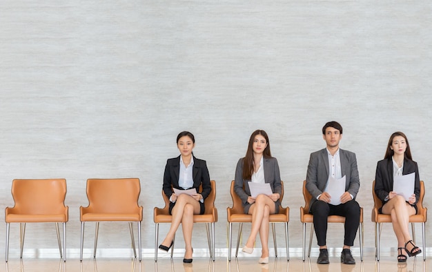 Candidates sitting on chair by wall for interview