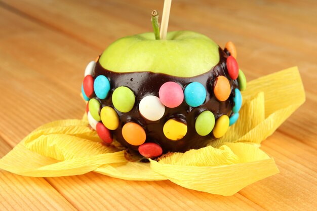 Candied apple on stick on wooden table