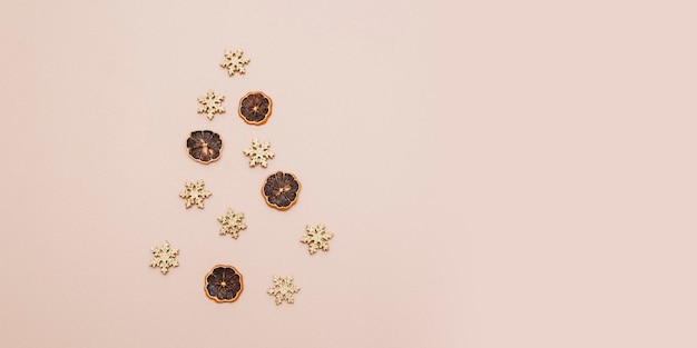 Candied citrus fruits and golden snowflakes are laid out in the shape of a Christmas tree on a beige background Minimalistic greeting card for New Year and Christmas Copy space Flatley Top view