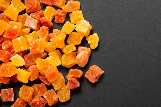 Candied fruits pineapple and papaya on black background