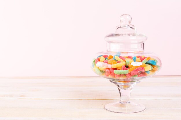 Candies in candy jar on wood table.