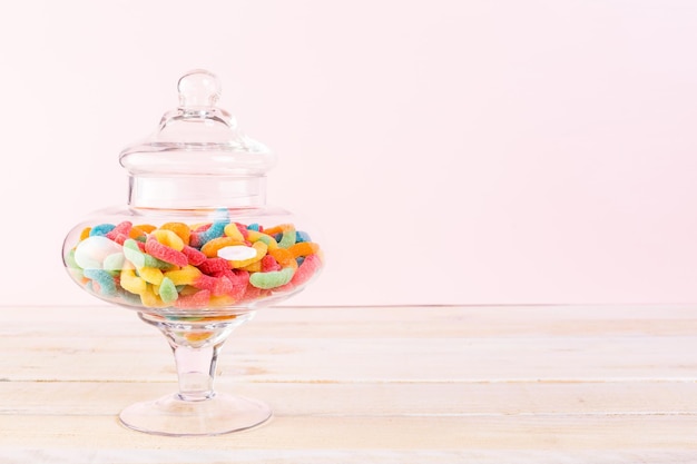 Candies in candy jar on wood table.