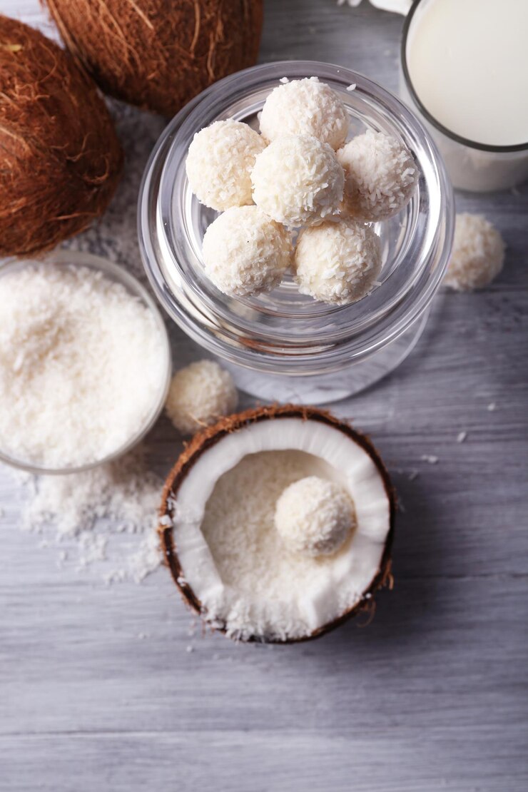 Photo candies in coconut flakes and fresh coconut on color wooden background