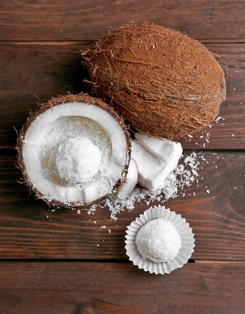 코코넛 플레이크에 있는 사탕과 어두운 나무 배경에 신선한 코코넛