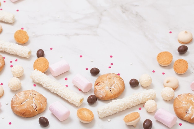 Candies and cookies on white marble background