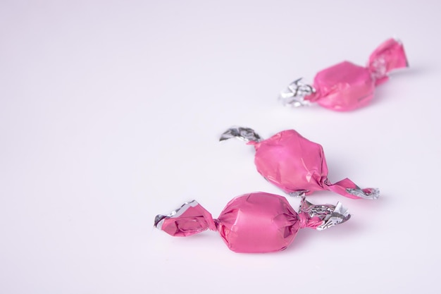 Photo candies in pink candy wrappers on a white background copy space