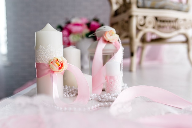 Candle are decorated with pink bow, ribbon and greens stand on the festive table newlyweds covered with a tablecloth. flat lay. top view. Wedding inspiration. Close up. Artwork. Decor. Details.