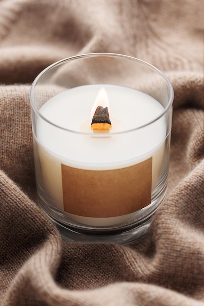 A candle burns on the background of a knitted sweater