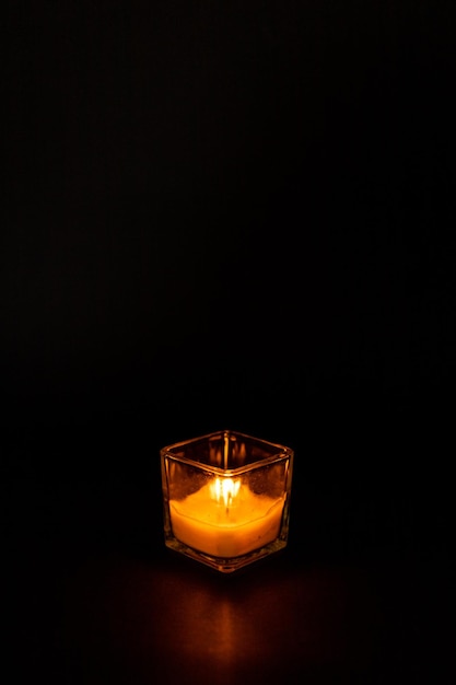 Candle in a glass beaker on a black background