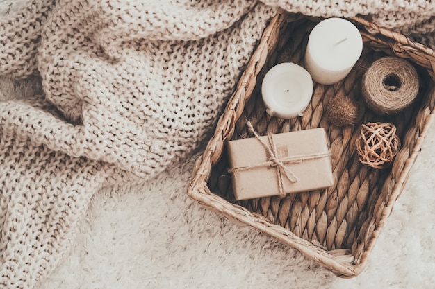 Candle and knitting clothes in wicker basket