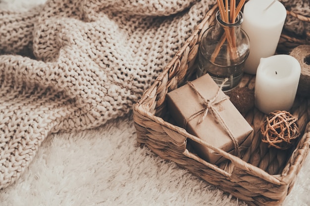 Candle and knitting clothes in wicker basket.