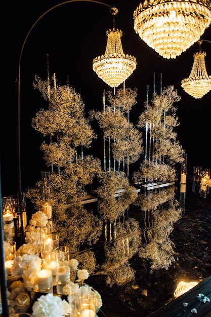 Photo candle light in glass lanterns and gorgeous lamp at luxury wedding ceremony in evening, decor and arrangements.