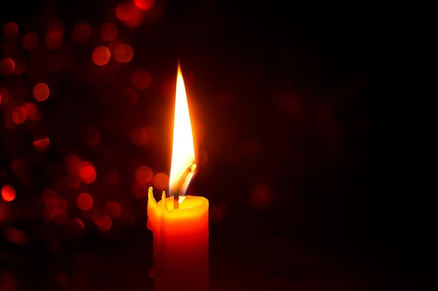 Candle light with festive bokeh on black background Holiday and religious ideas