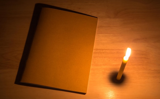 Candle light with note book on the wooden table in the dark night picture for art work design or add text message
