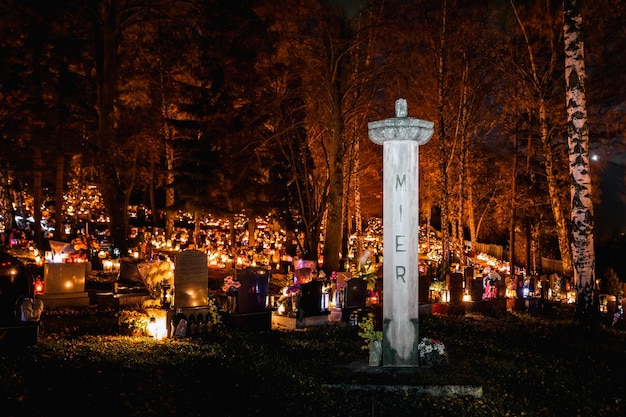 Candle lights on graves and tombstones in cemetery at night on All Souls Day