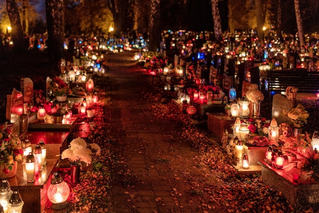 Candle lights on graves and tombstones in cemetery at night on All Souls Day