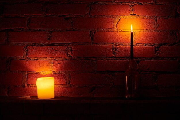 Candle lights on loft wall background. Yellow and red fire in wax candles