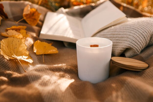 Candle and open book in nature autumn concept